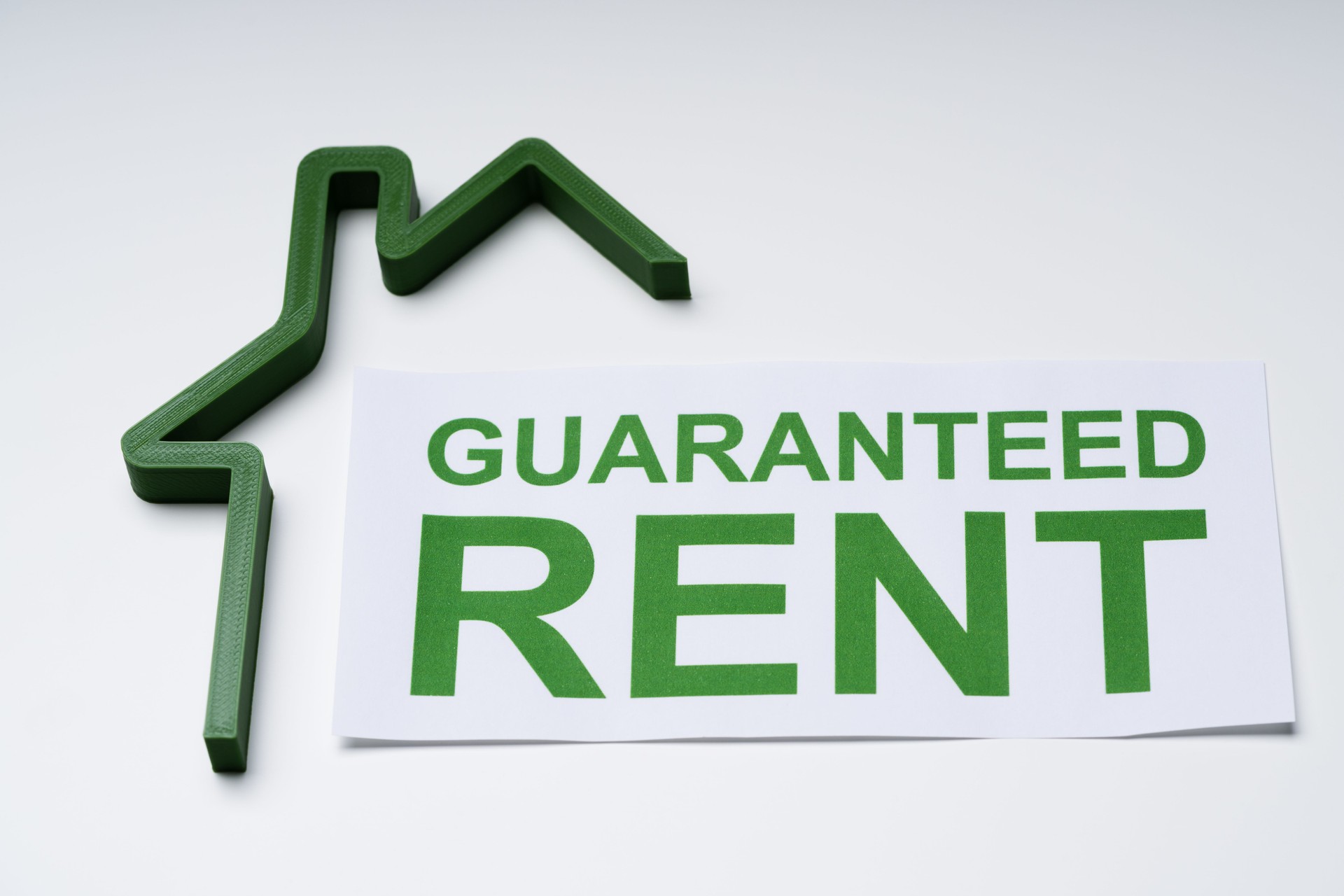 Green House Model And Paper With Guaranteed Rent Text